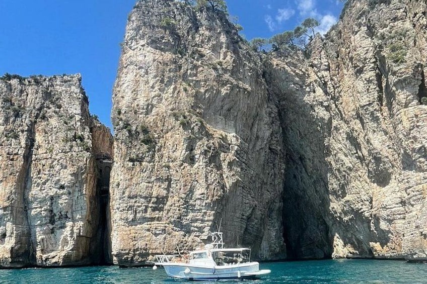 Un bateau près de falaises rocheuses, sur une mer bleue et limpide. 3