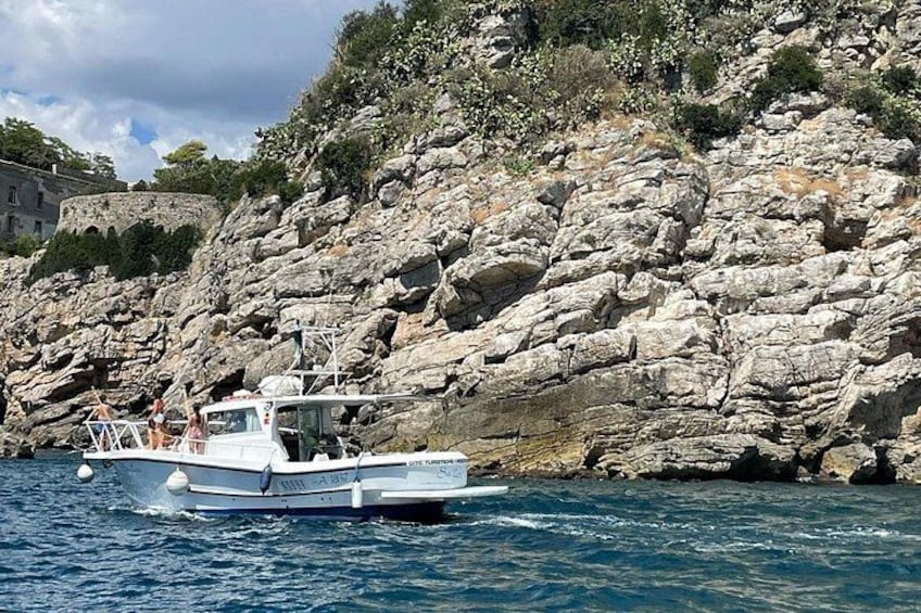 Un bateau sur une côte rocheuse, avec une eau d’un bleu limpide. 2