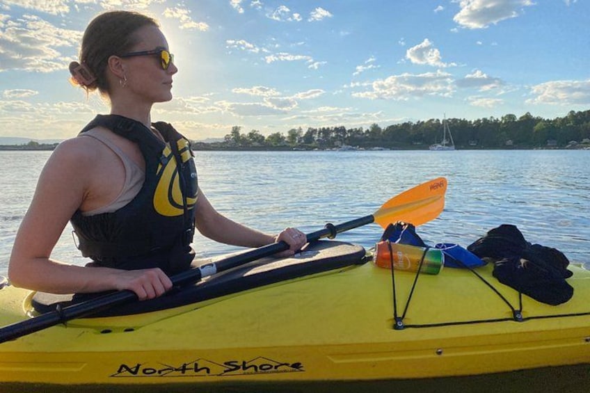 Una persona en un kayak amarillo con un remo, usando chaleco salvavidas y una botella de agua en el kayak. 2