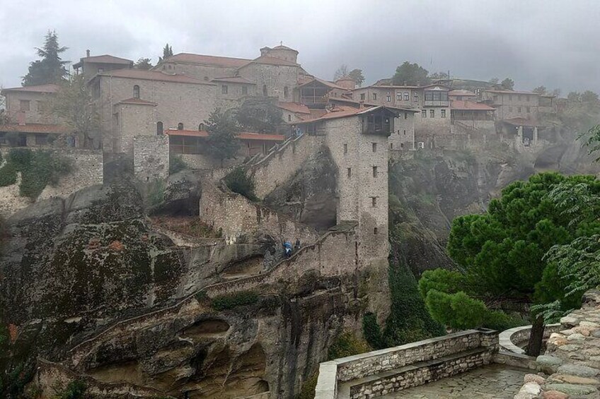 A historic stone fortress with multiple buildings perched on a rocky cliff. 1