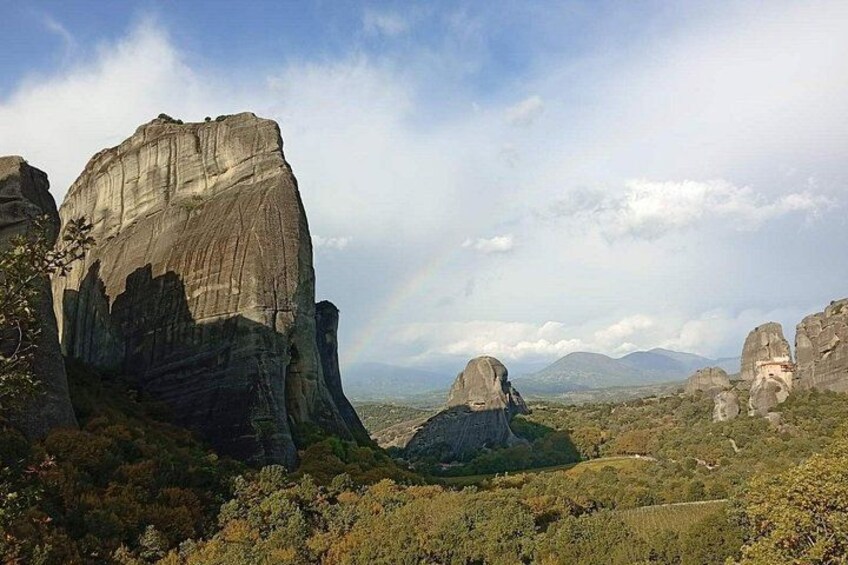 A landscape with large rock formations, a valley, and distant mountains under a partly cloudy sky. 2
