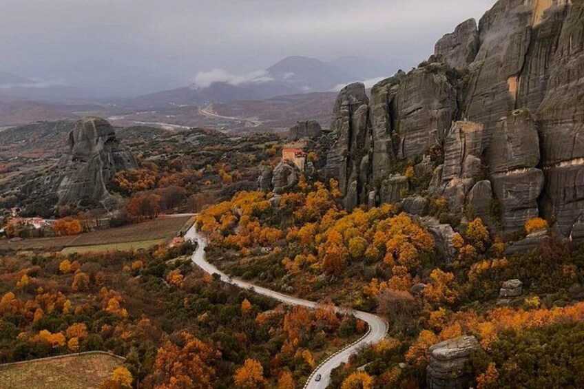 A winding road through a mountainous area with autumn-colored trees and rocky cliffs. 4