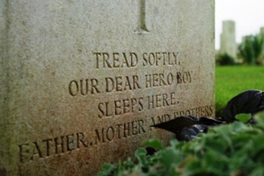 A gravestone with an inscription, surrounded by greenery. 3