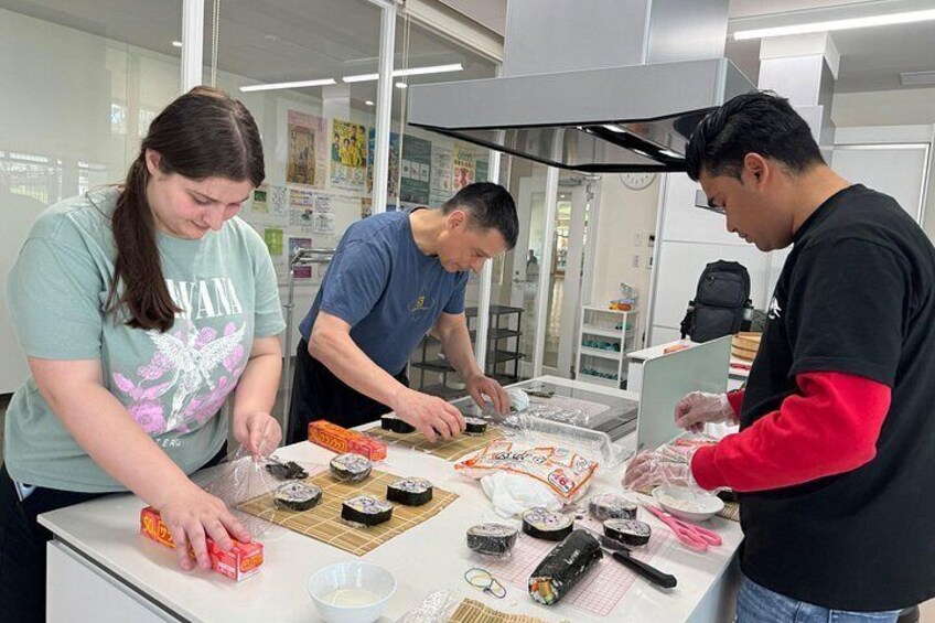 Three people preparing sushi in a kitchen. 3