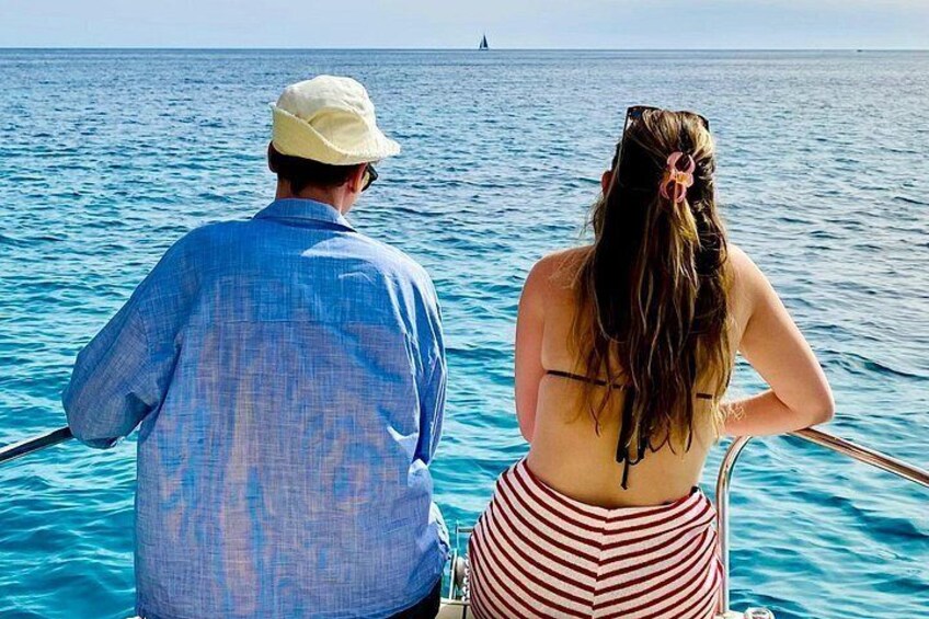 A man and a woman on a boat, facing the ocean. 3