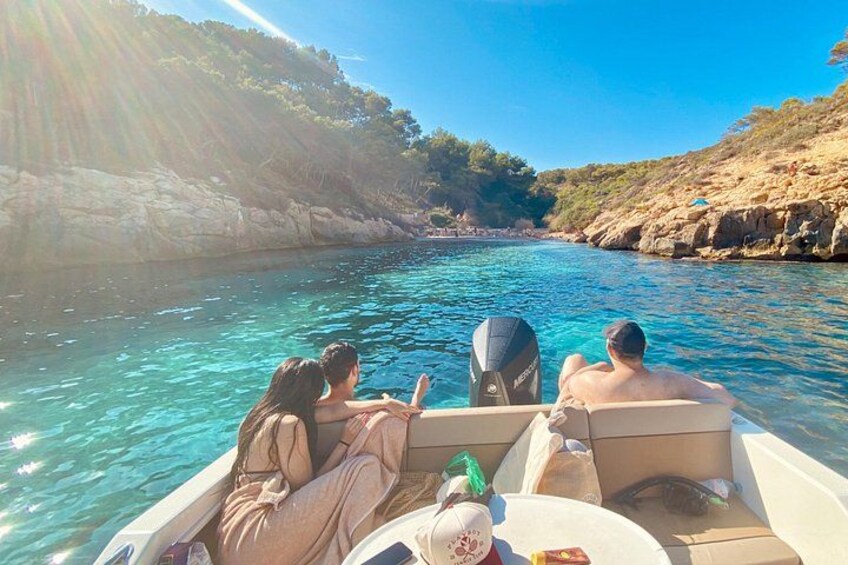 Un barco en un mar azul y despejado con acantilados rocosos al fondo. 5