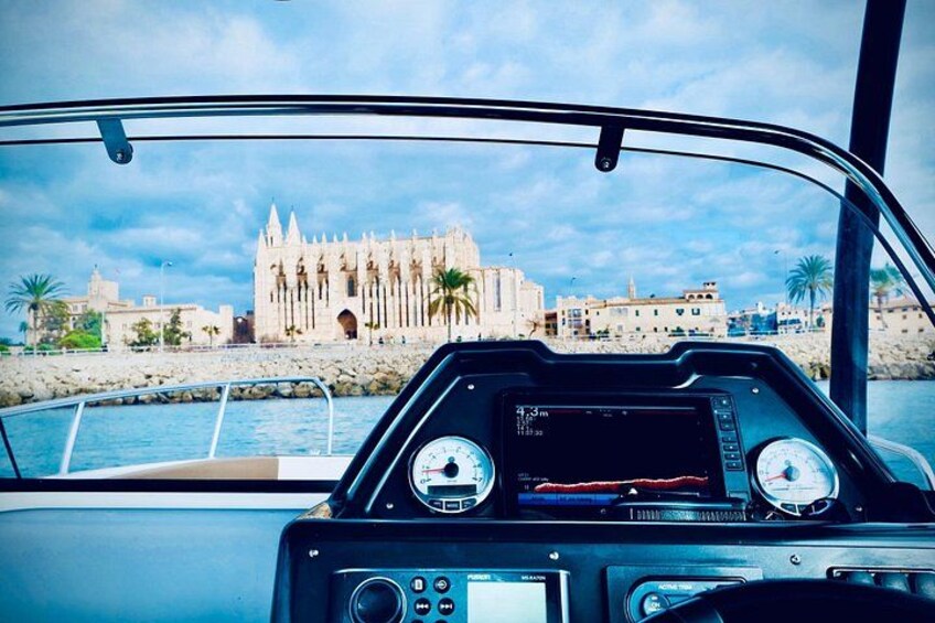 Cabina de barco con pantalla GPS, timón y vista de un edificio histórico junto al agua. 2