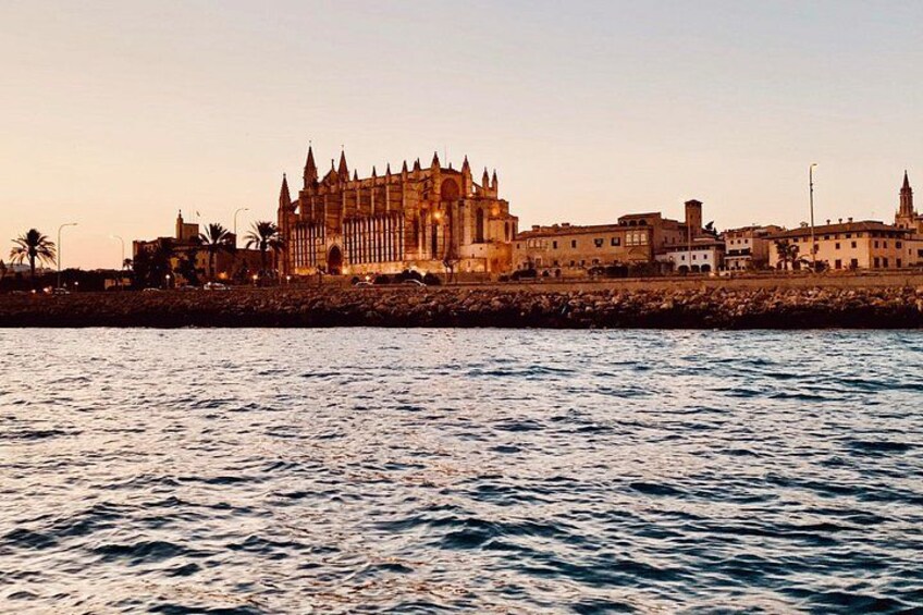 Un paisaje urbano costero con un edificio prominente de estilo catedralicio, un paseo marítimo y un cielo despejado. 3