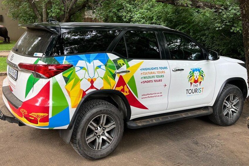 Een witte SUV met opvallende reclameborden voor toeristische excursies. 1