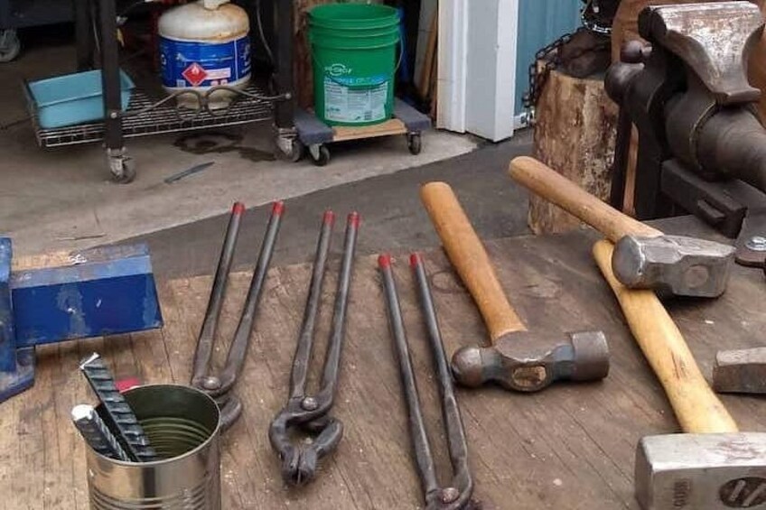 Un taller con herramientas como martillos, llaves inglesas y un tornillo de banco sobre una mesa de madera. 2