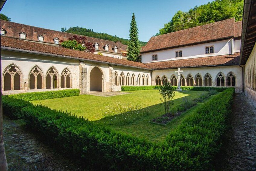 A cloister with a central courtyard, arched walkways, and a cross at the end. 4