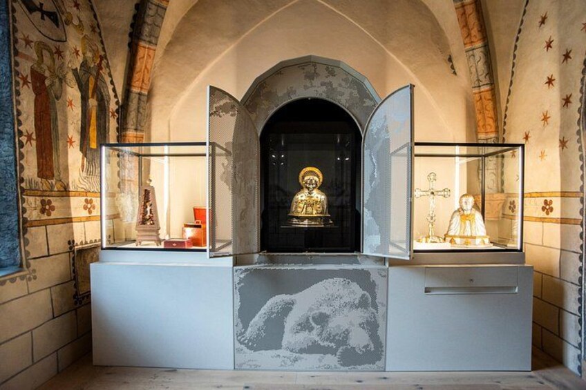 A religious shrine with a statue, a cross, and a glass display case. 2