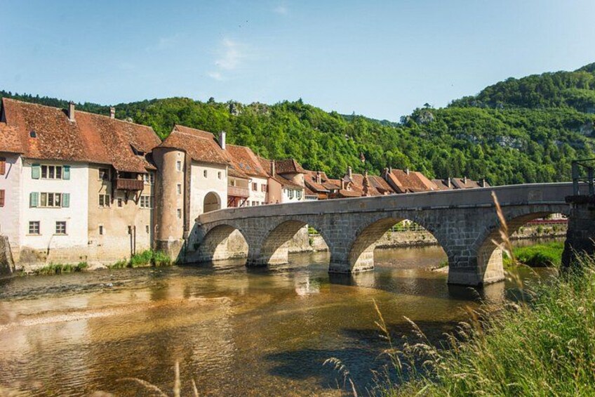 A stone bridge over a river, surrounded by traditional buildings with red-tiled roofs. 3