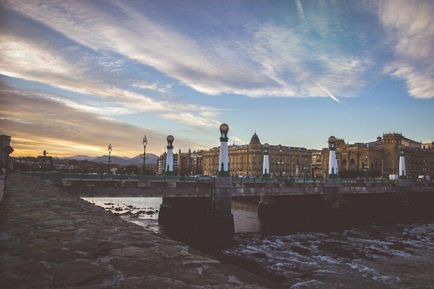 A bridge with lamp posts, a river, and historic buildings in the background. 3