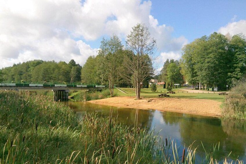 A pond, a bridge, trees, and picnic tables. 3