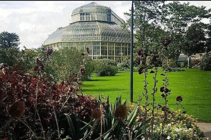 Ein Gewächshaus mit Kuppelbau, umgeben von einem gepflegten Garten mit verschiedenen Pflanzen und Blumen. 4