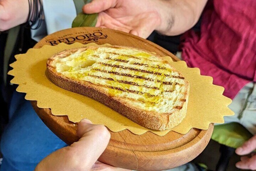 Un sándwich de queso a la plancha sobre una tabla de madera con un rótulo que dice "REDORO". 1