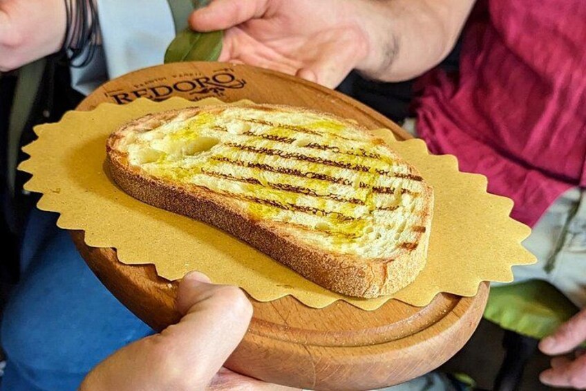 Una persona tiene in mano un tagliere con un panino alla griglia sopra. 3