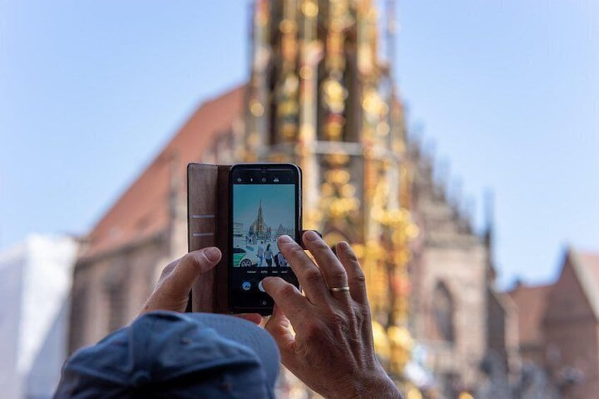 Une personne tenant un téléphone intelligent et prenant une photo d’un bâtiment doté d’une façade dorée et d’un clocher. 5
