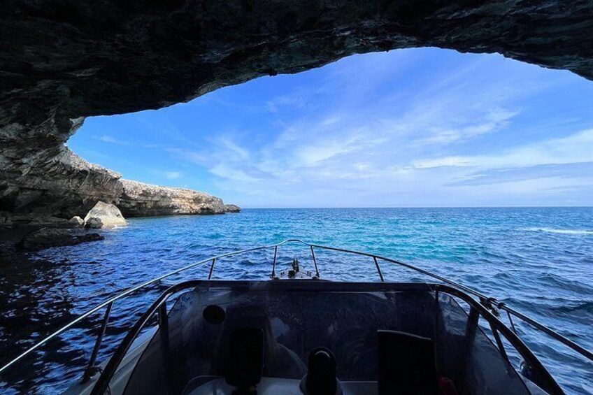 A boat navigating through a rocky cove with clear blue water and a distant shoreline. 4