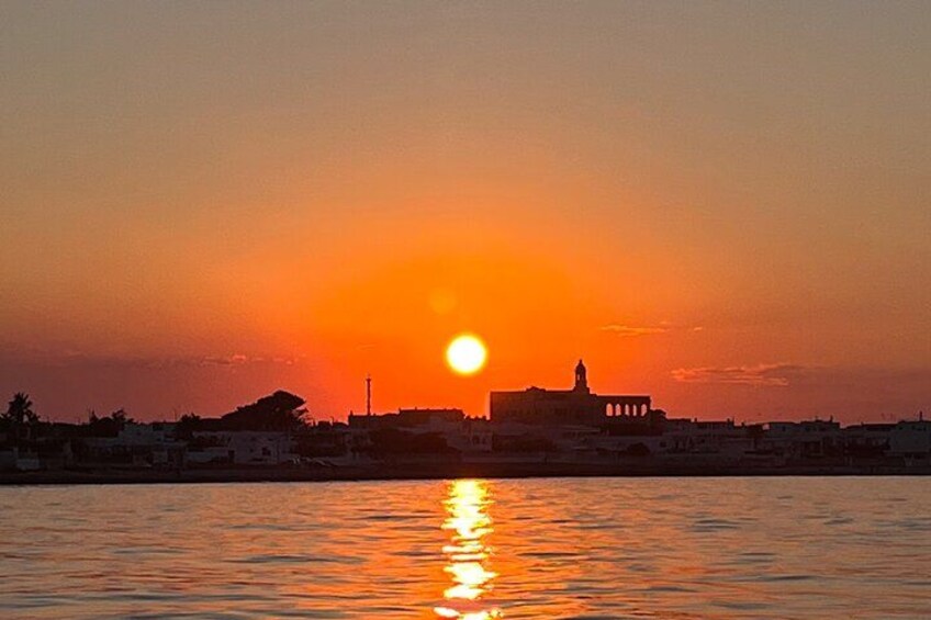 A sunset over a body of water with a silhouette of a building and a bridge. 4