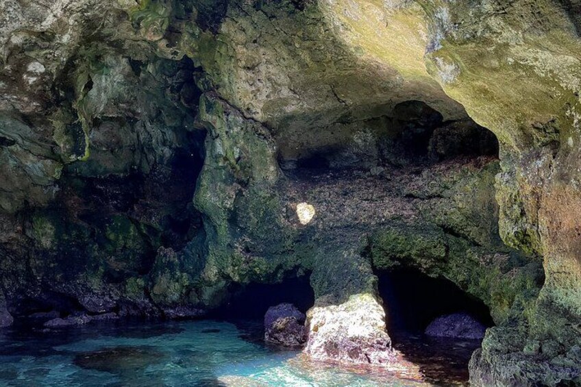 A cave with clear water, rock formations, and a small opening. 2