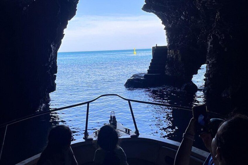 A boat navigating through a rocky coastal area with a clear view of the sea. 2