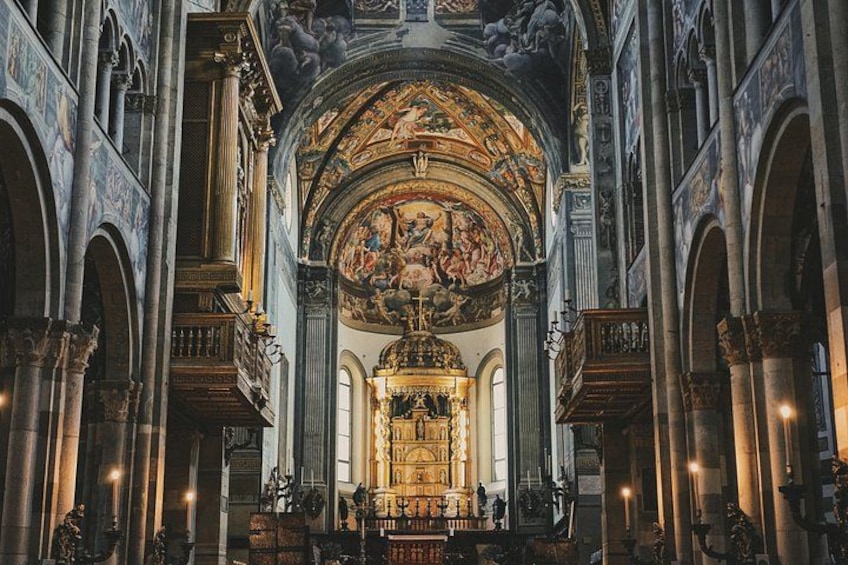 Un vaste intérieur de cathédrale, avec de hauts plafonds en voûte, des colonnes richement décorées et un autel central. 3
