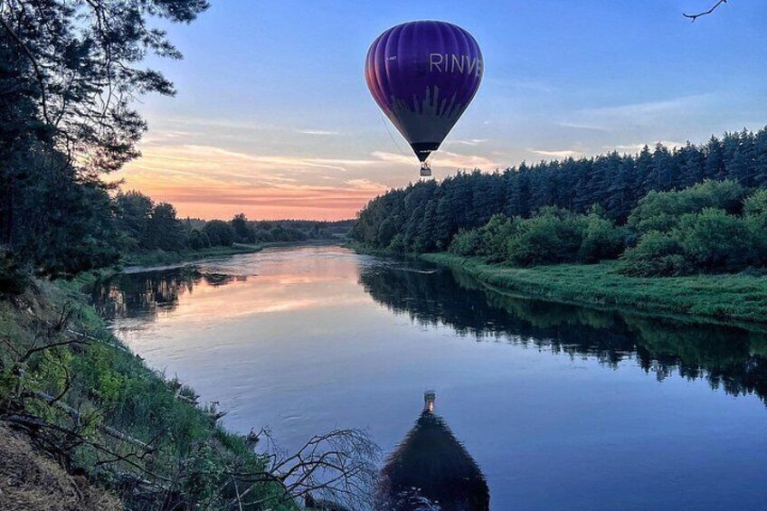 A hot air balloon over a calm river with dense forest on both sides. 3