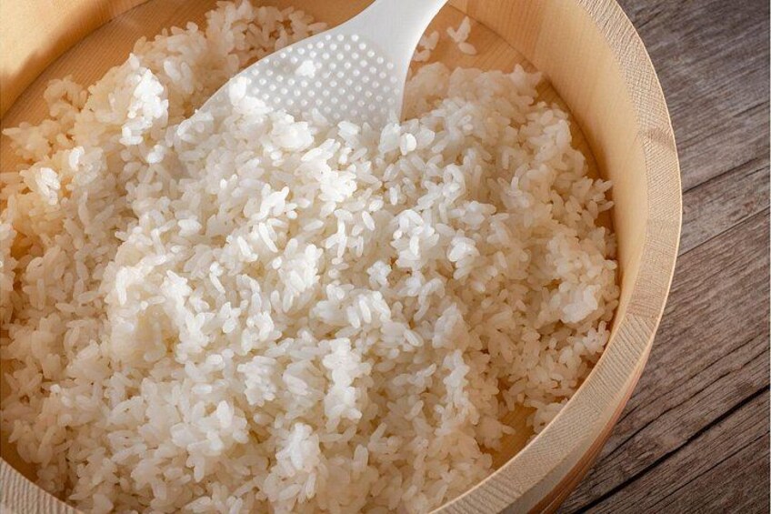 Un bol en bois rempli de riz blanc et une cuillère en plastique blanche. 3