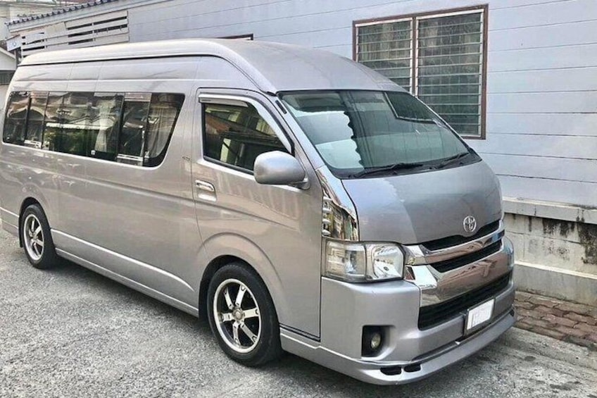 En silverfärgad Toyota-skåpbil stod parkerad framför en byggnad med ett fönster och en dörr. 4