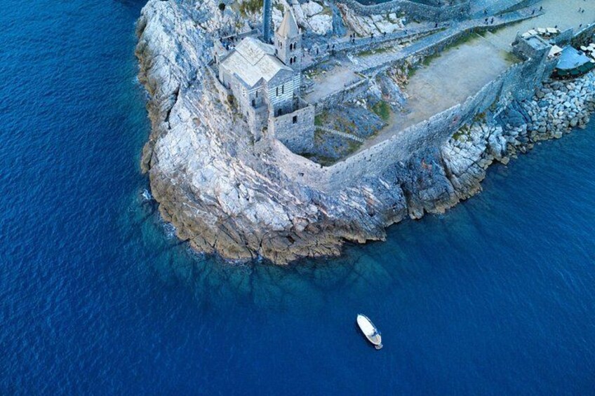 An aerial view of a rocky island with a small building and a boat in the water. 2