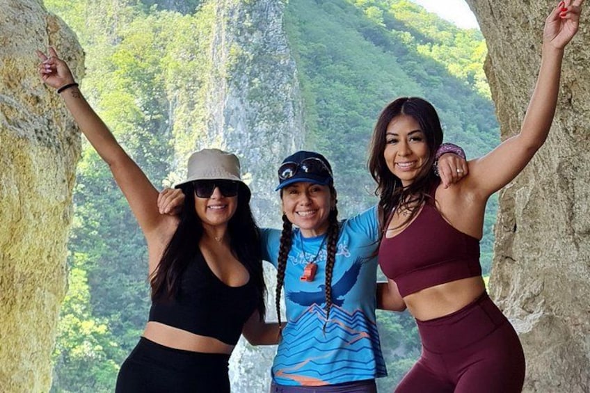 Three people standing on a rocky ledge with a mountainous landscape in the background. 3