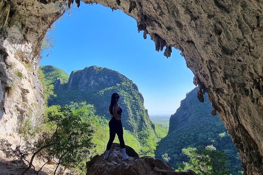 A person standing in a natural rock formation with a view of a mountainous landscape. 4