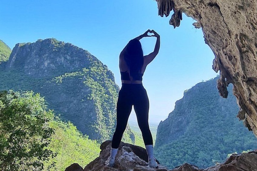 A person standing on a rock formation with a cave-like structure in the background. 1