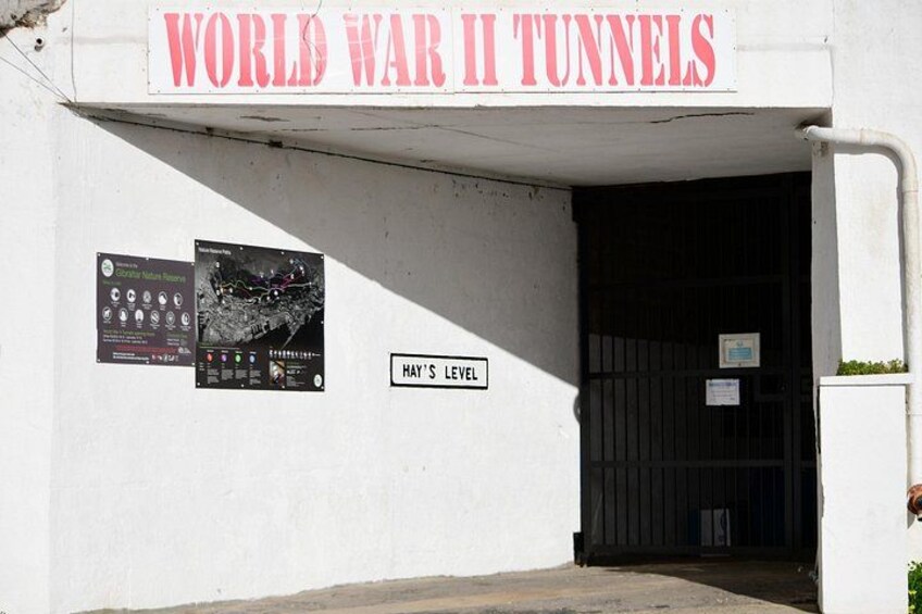 A building entrance labeled 'WORLD WAR II TUNNELS' with a sign for 'HAY'S LEVEL' and informational posters. 2