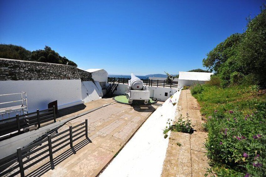 A coastal walkway with a white wall, a stone wall, and a green railing. 5