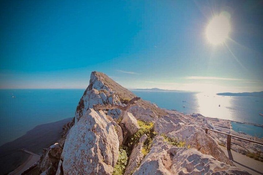 A rocky coastline with a clear sky and the sun shining. 1