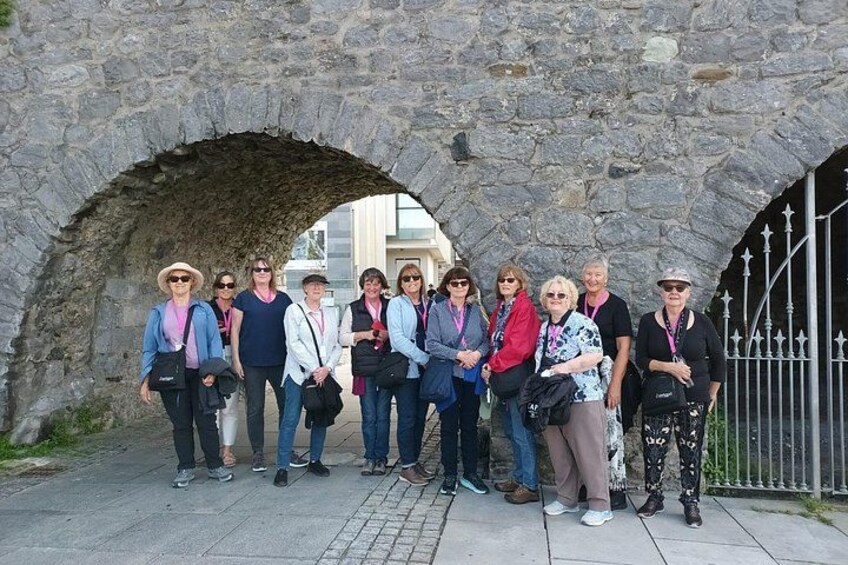 Un grupo de personas de pie bajo un arco de piedra. 2