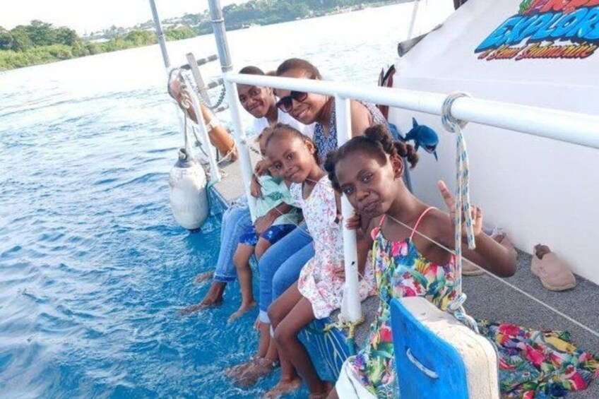 A group of people on a boat with a clear blue sea in the background. 2