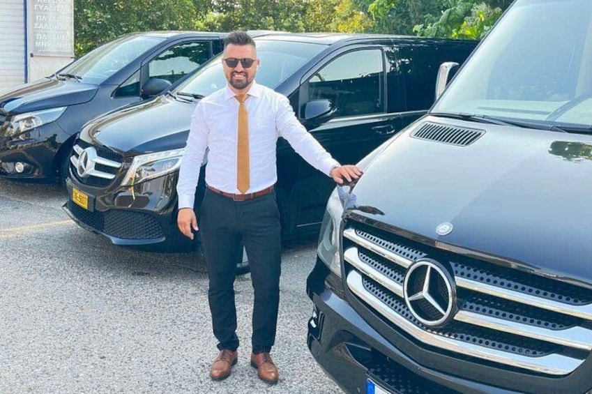 A man standing next to a black Mercedes-Benz SUV in a parking lot. 1