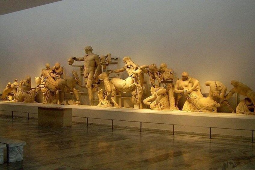 A large marble sculpture of a battle scene with multiple figures, including soldiers and horses, in a museum setting. 5