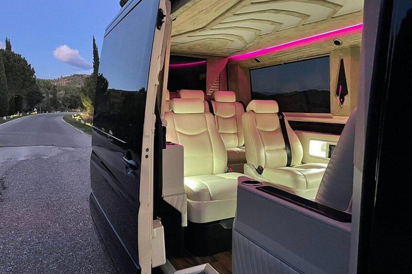 A luxury bus interior with plush seating and ambient lighting. 4