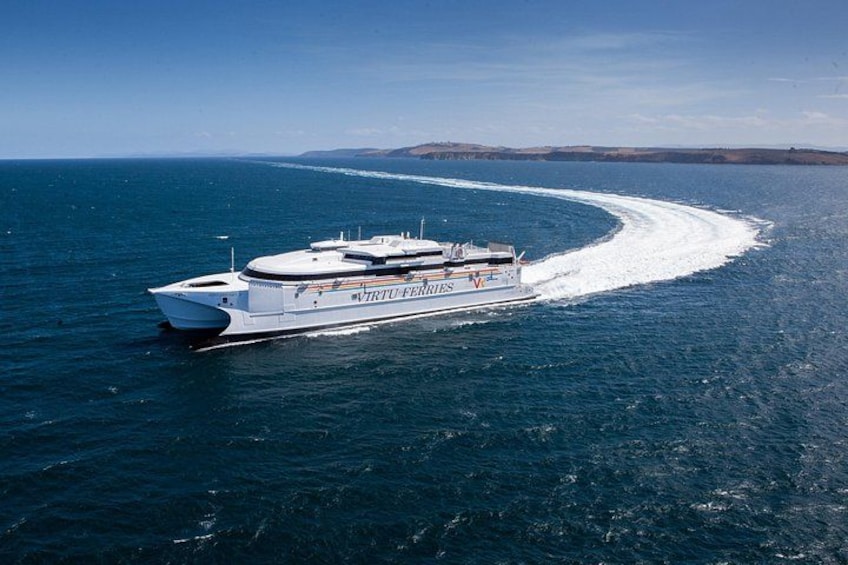 Een groot wit cruiseschip genaamd 'NTRU FERRIES' vaart over een heldere blauwe oceaan. 2
