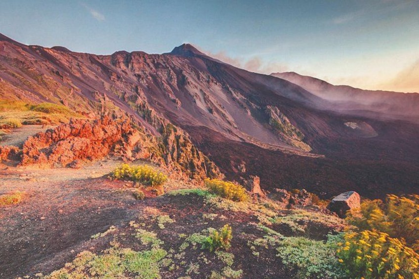 Een bergachtig landschap met rotsachtig terrein, schaarse begroeiing en een heldere lucht. 5