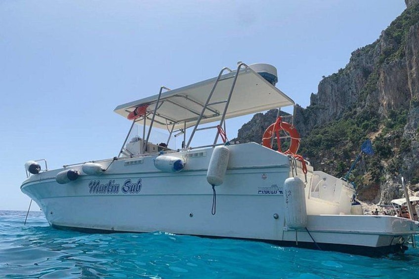 Un barco blanco llamado Martin Sub atracado cerca de una costa rocosa. 5