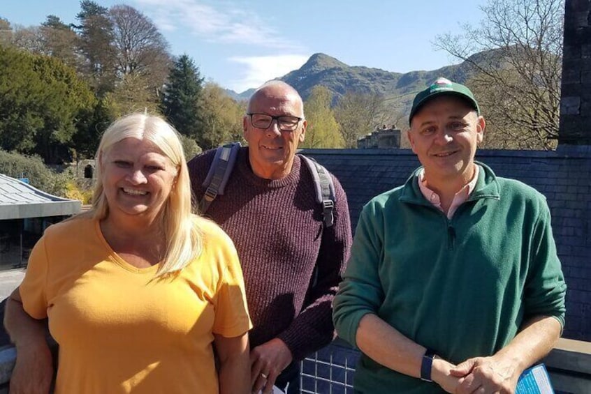 Three people standing outdoors with mountains in the background. 1