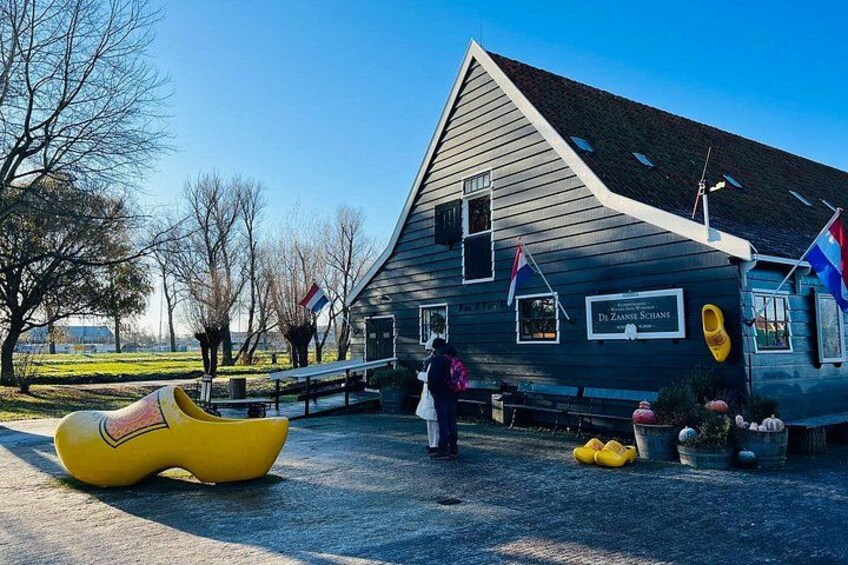 Un bâtiment en bois, une enseigne, une sculpture représentant une chaussure jaune et un drapeau. 5