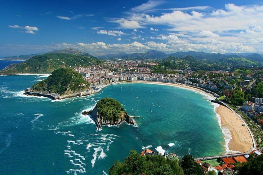 A coastal city with a bay, a small island, and a mountain range in the background. 1