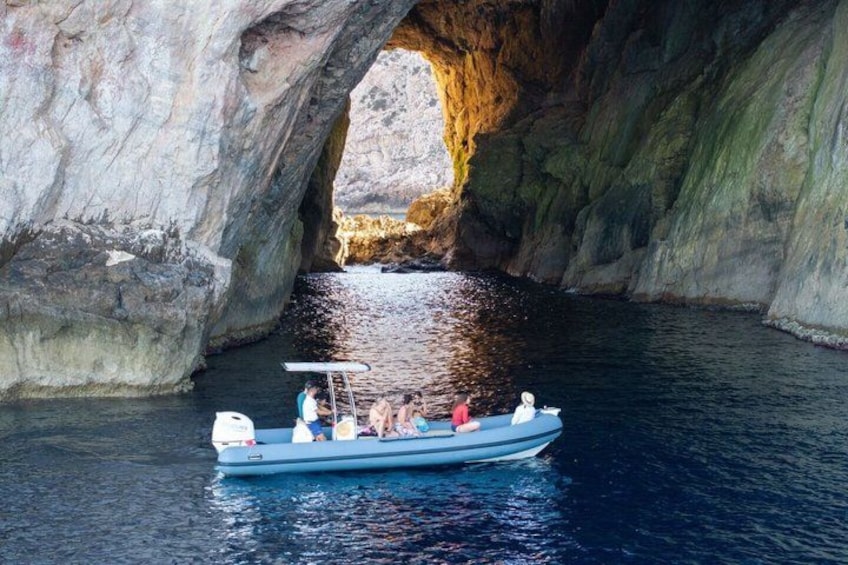 Un bote con pasajeros navegando por una formación rocosa natural en forma de arco. 5